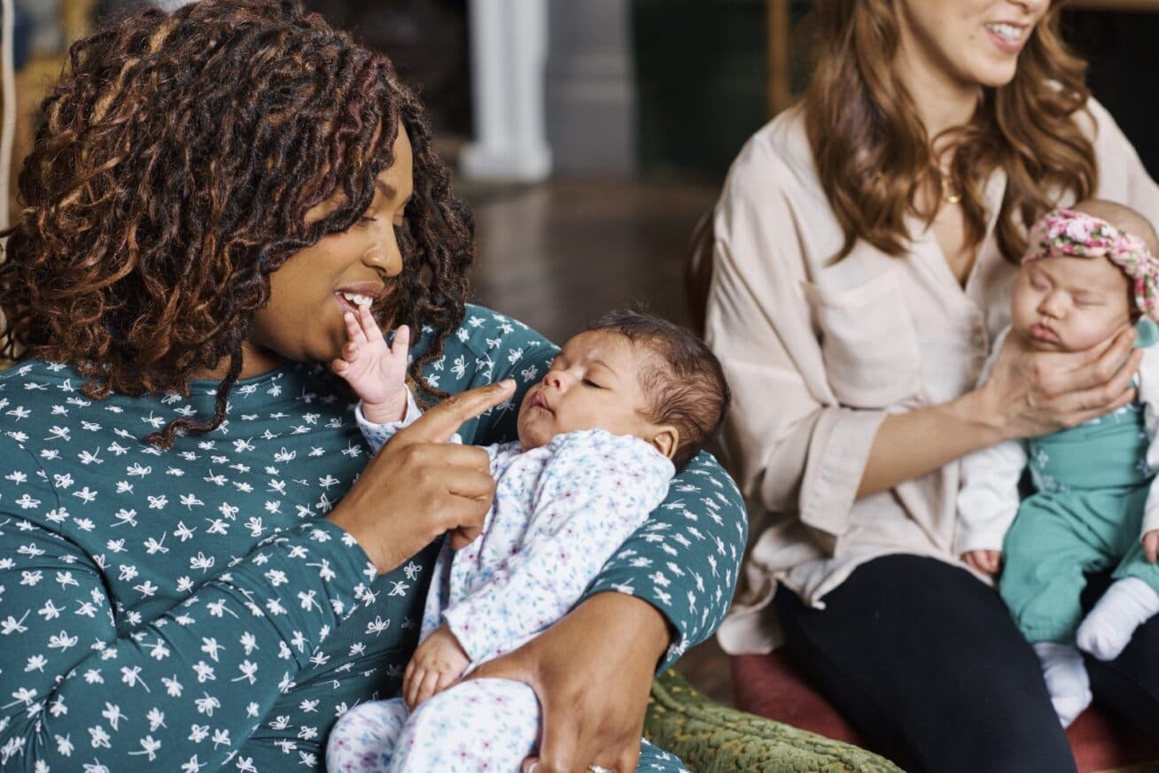 Image shows two mothers holding an infant